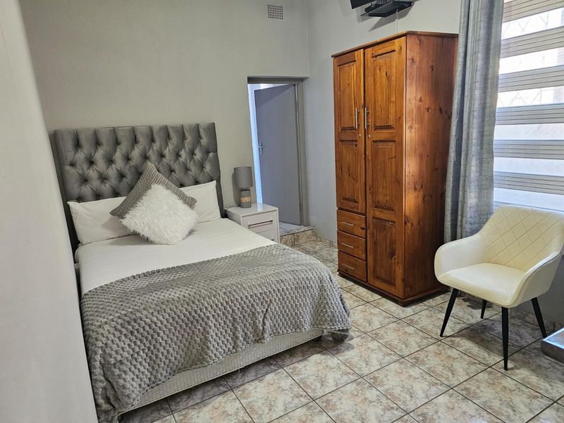 A bedroom featuring tiled flooring and a window with fitted blinds, providing a functional living space.