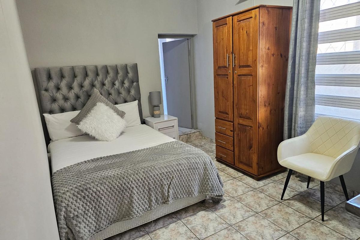 A bedroom featuring tiled flooring and a window with fitted blinds, providing a functional living space.