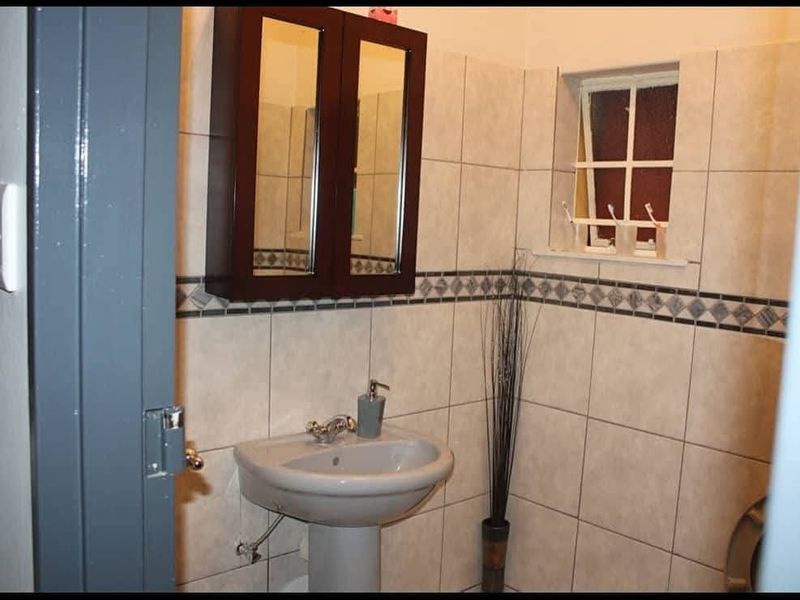 A functional bathroom featuring a pedestal basin, wall-mounted medicine cabinet, and tiled wall finishes.
