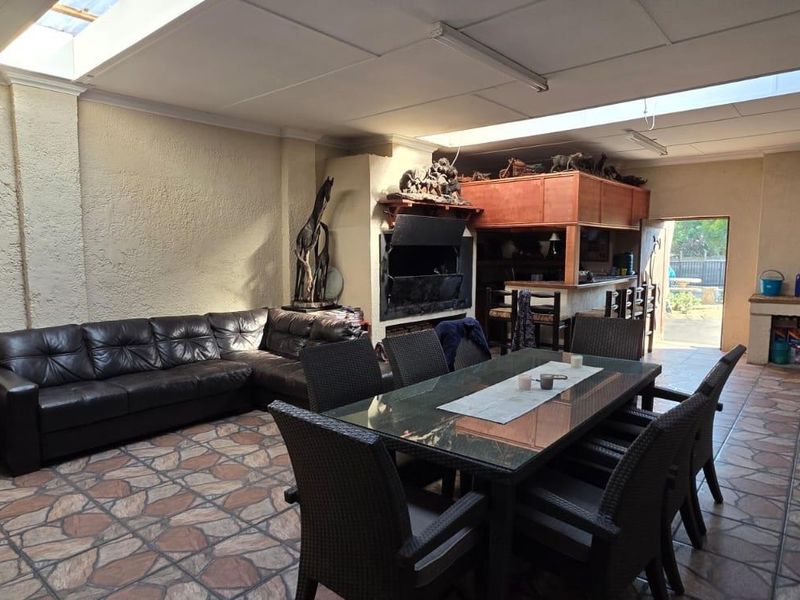 Spacious covered patio featuring a built-in braai, bar area, and skylights, providing a versatile space for outdoor entertaining and dining.