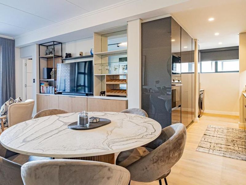 Modern open-plan living and kitchen area featuring high-end cabinetry, stone countertops, integrated appliances, and seamless access to an outdoor patio.