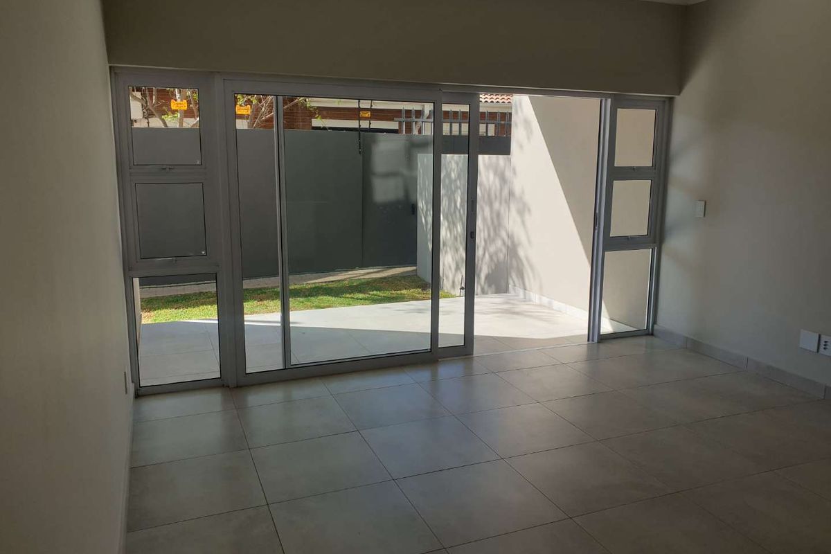 Bright living area featuring large sliding glass doors that open onto a private patio and garden space.