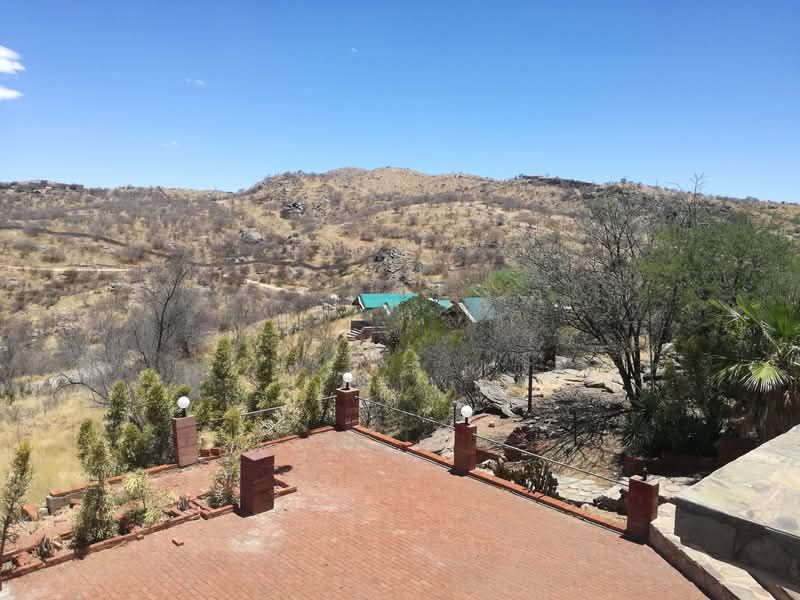 An elevated brick-paved terrace featuring brick pillars and cable railings, offering expansive views of the surrounding arid landscape.