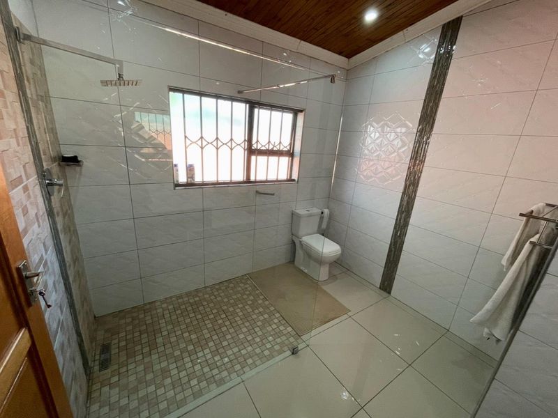 Modern bathroom featuring a spacious walk-in shower with glass screen, tiled finishes, and a timber ceiling.