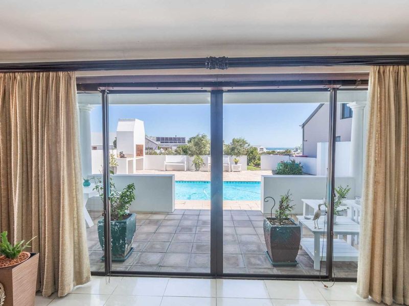 Living area featuring large sliding glass doors that open onto a patio with a swimming pool and built-in braai area.