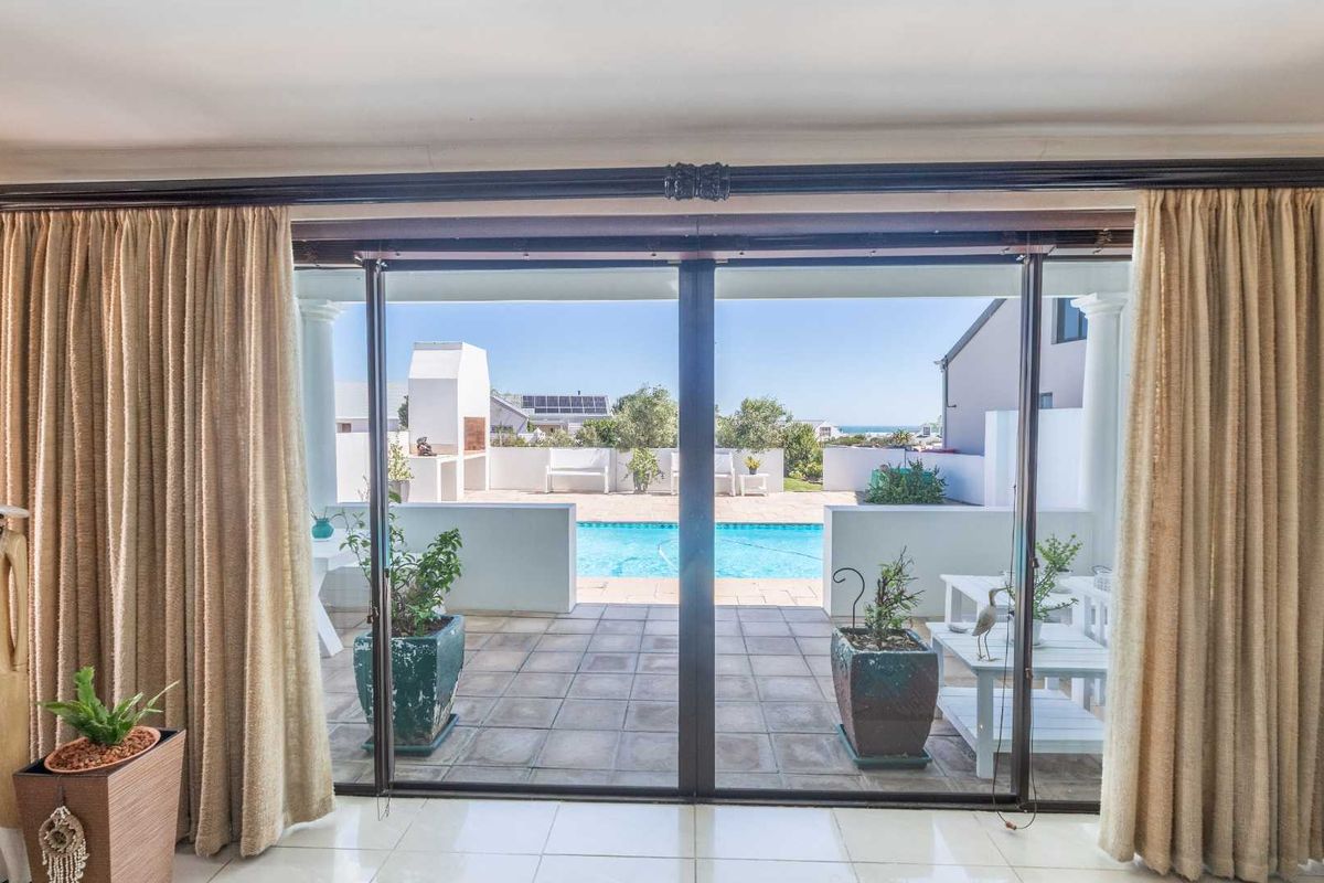 Living area featuring large sliding glass doors that open onto a patio with a swimming pool and built-in braai area.