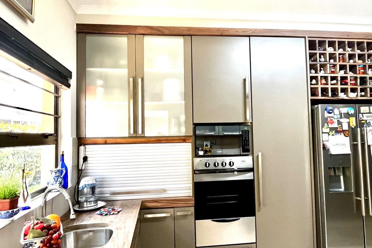 Modern kitchen featuring sleek cabinetry, integrated oven and microwave, wood-look countertops, and a dedicated wine storage rack above the refrigerator space.