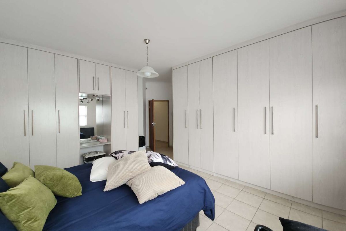 A spacious bedroom featuring extensive floor-to-ceiling built-in cabinetry with integrated vanity and tiled flooring.