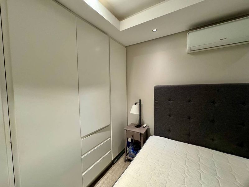 A well-maintained bedroom featuring a floor-to-ceiling built-in wardrobe, recessed ceiling lighting, and a wall-mounted split-system air conditioning unit.