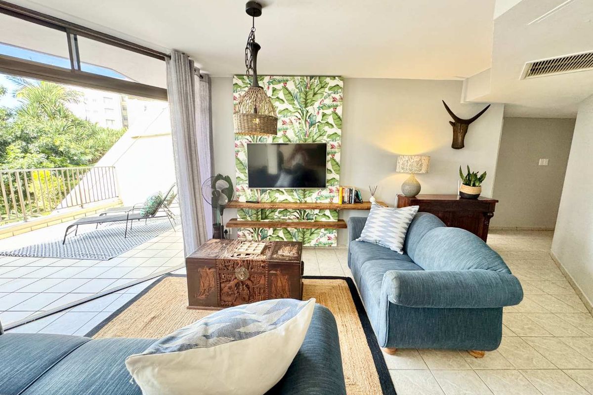Bright living room featuring tiled flooring, built-in shelving, and large sliding doors opening onto a private balcony.