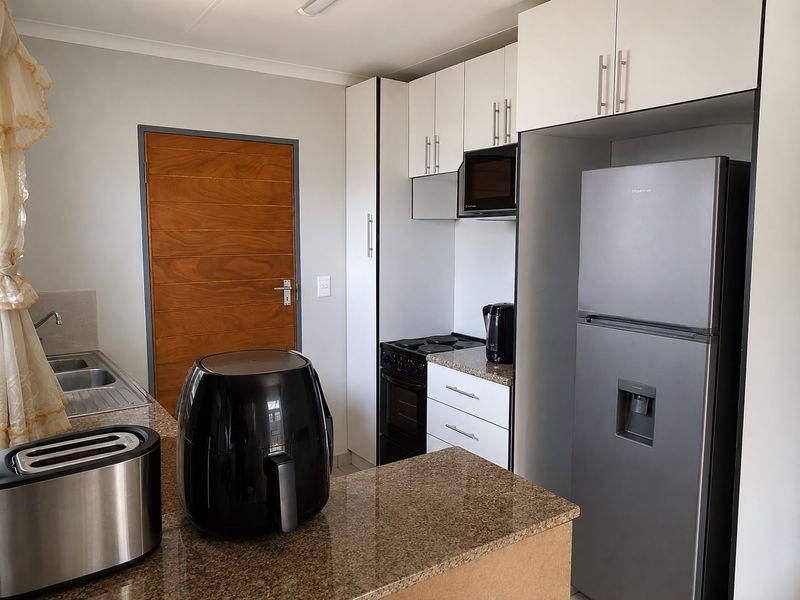 A functional kitchen featuring granite countertops, white cabinetry, and built-in appliances, providing a clean and practical workspace.
