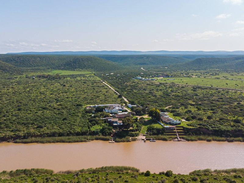 Aerial view of a riverside property featuring private jetty access and boat slipway, set within a vast natural landscape.