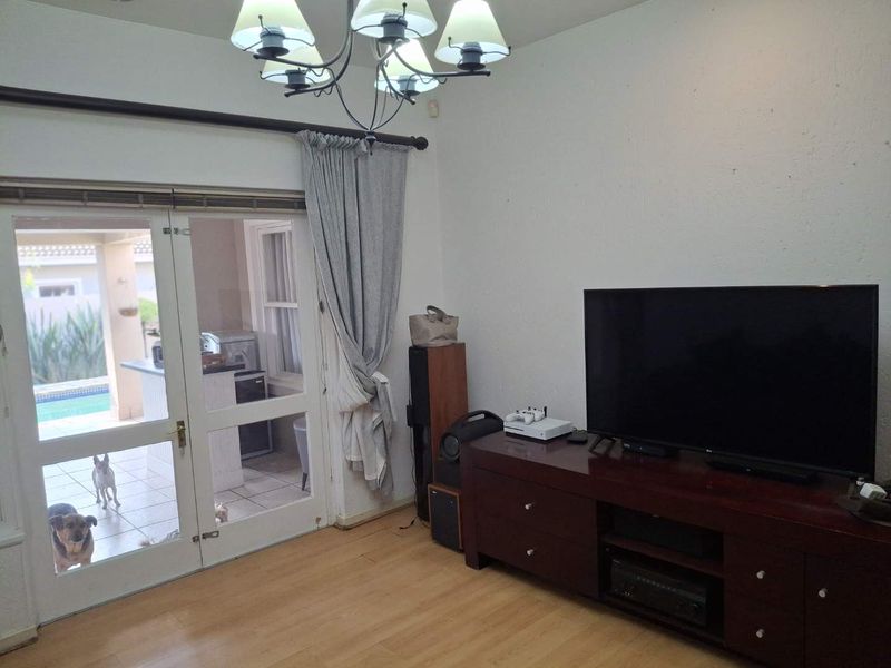 A living room featuring laminate flooring and a double glass door providing access to the outdoor patio area.