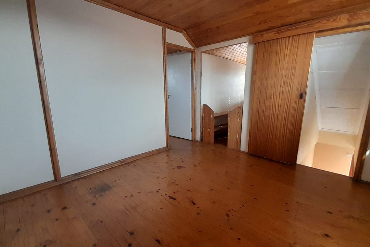 An empty bedroom featuring original timber flooring, wood-paneled ceilings, and built-in sliding door storage, offering a blank canvas for renovation.