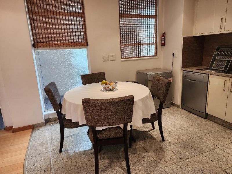 A functional kitchen area featuring built-in cabinetry, tiled flooring, and an integrated dishwasher, providing a practical space for meal preparation and dining.