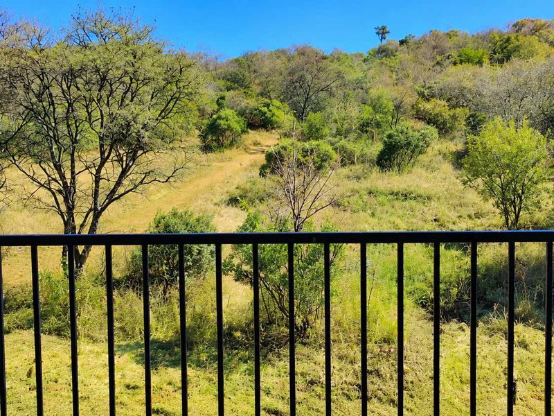 A scenic view of the natural landscape and hillside, framed by a black metal balustrade.