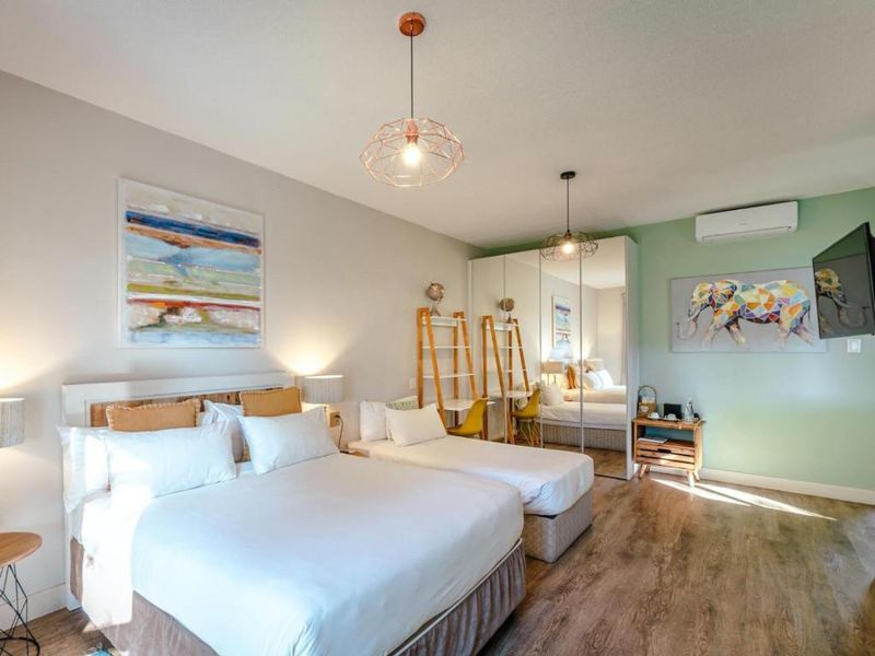 A well-maintained bedroom featuring laminate flooring, a mirrored built-in wardrobe, and a wall-mounted split-system air conditioner.