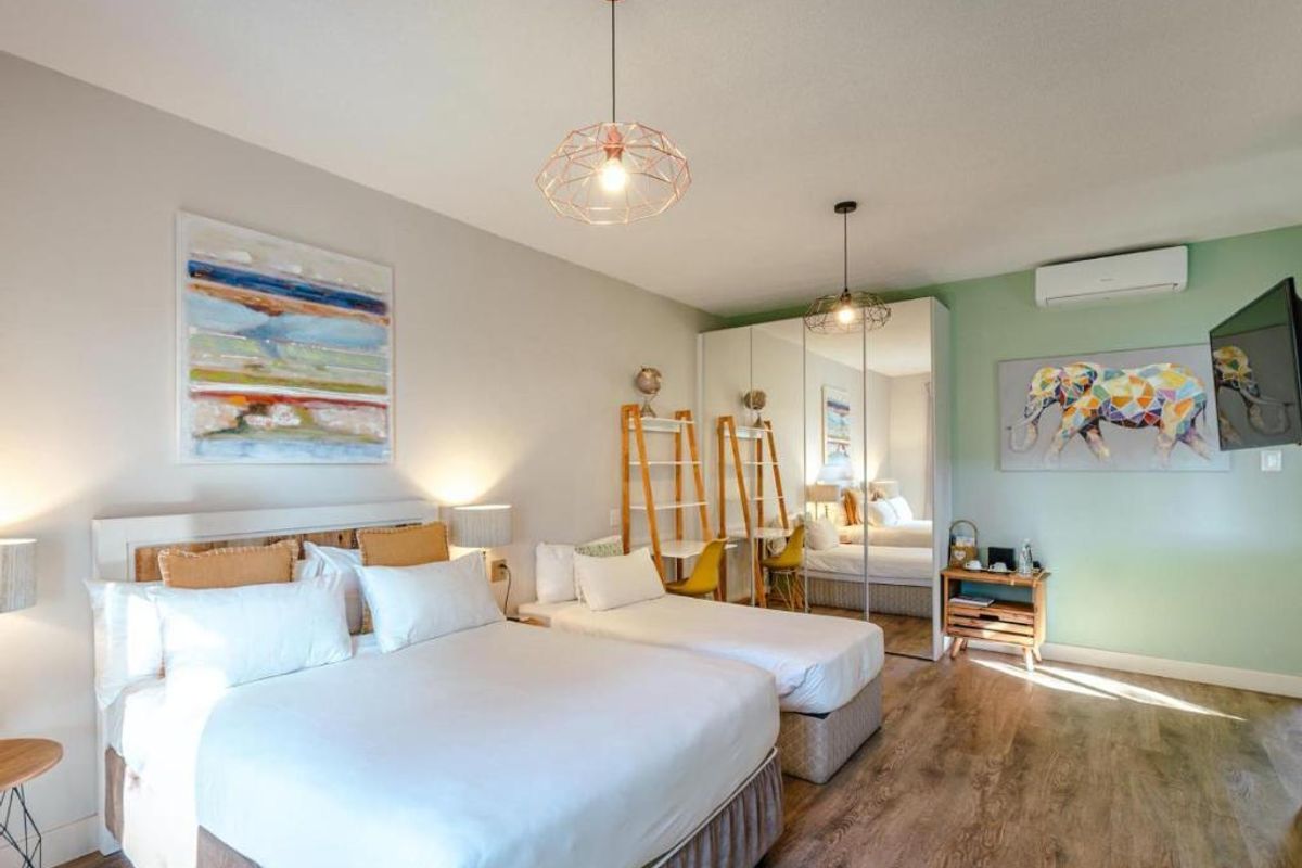 A well-maintained bedroom featuring laminate flooring, a mirrored built-in wardrobe, and a wall-mounted split-system air conditioner.