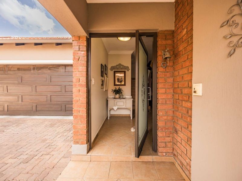 A welcoming entrance featuring a covered porch, brick detailing, and a glass-panelled front door leading into the home, adjacent to the garage.