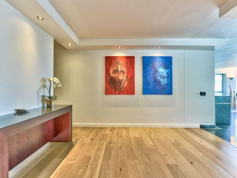 A bright and modern entrance hall featuring high-quality hardwood flooring, recessed downlighting, and a clean, minimalist aesthetic.