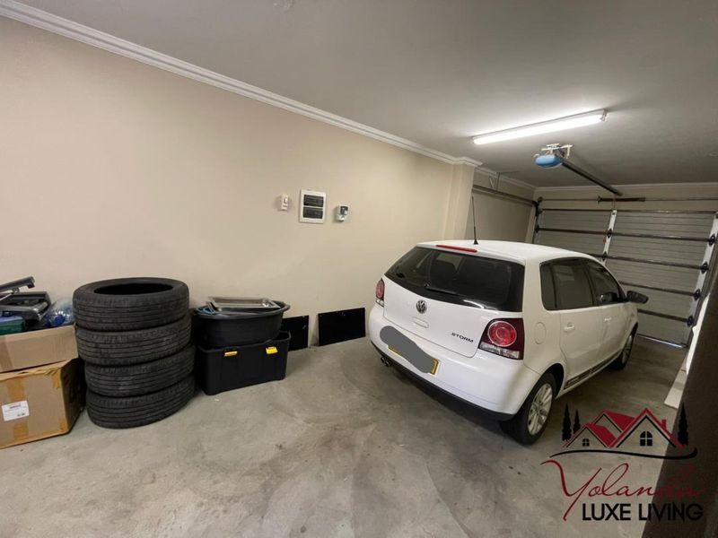 A functional single-car garage featuring an automated door, overhead lighting, and concrete flooring, providing secure parking and additional storage space.