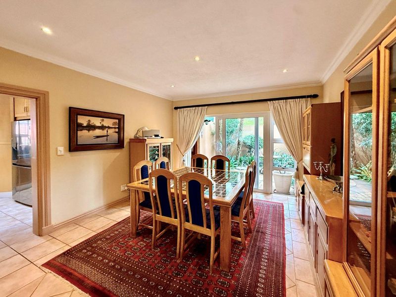 A dining room featuring ceramic floor tiles, recessed downlighting, and a sliding glass door providing access to the rear garden area.