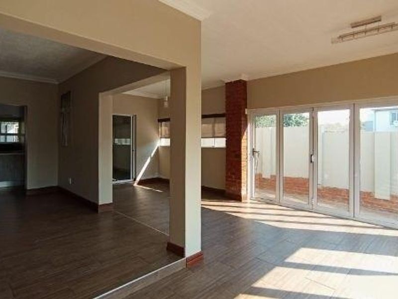 Spacious open-plan living area featuring tiled flooring, an exposed brick pillar, and large bi-fold glass doors providing seamless access to the exterior.