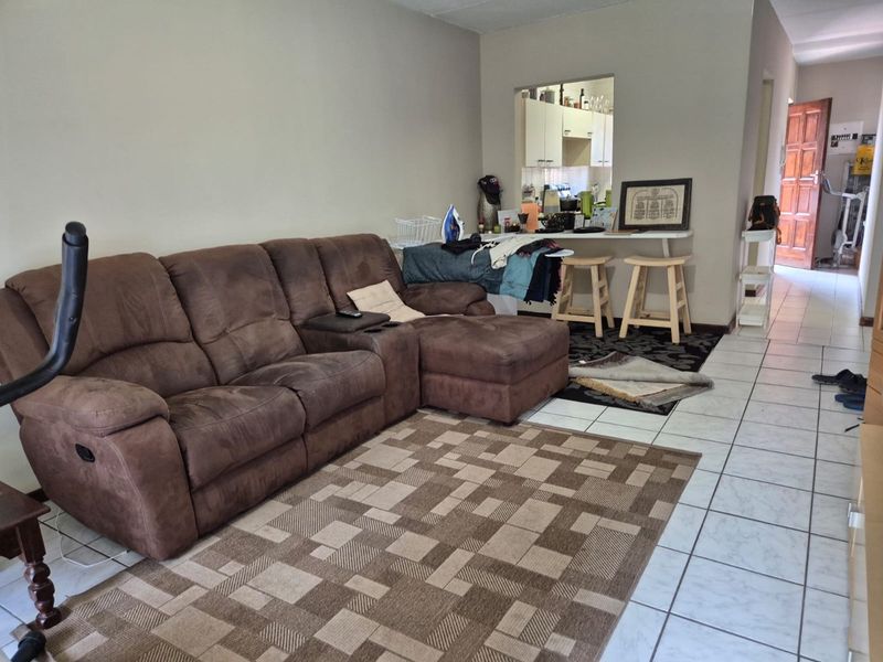 Open-plan living area featuring tiled flooring and a convenient pass-through window connecting to the kitchen space.