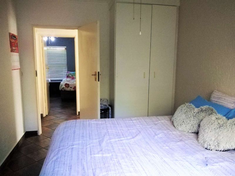 A bedroom featuring tiled flooring and a built-in wardrobe, with a doorway leading to an adjacent room.