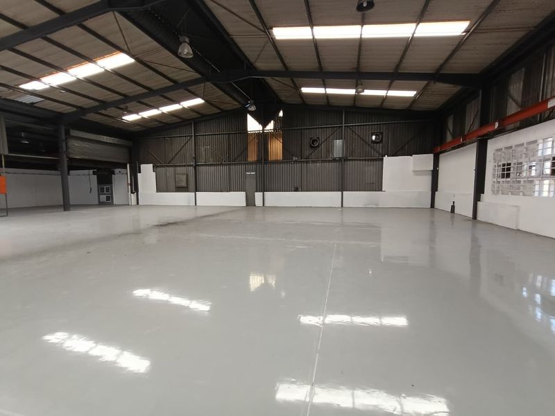 Spacious industrial warehouse featuring a polished epoxy floor, high-clearance steel portal frame, and ample natural light through integrated roof skylights.