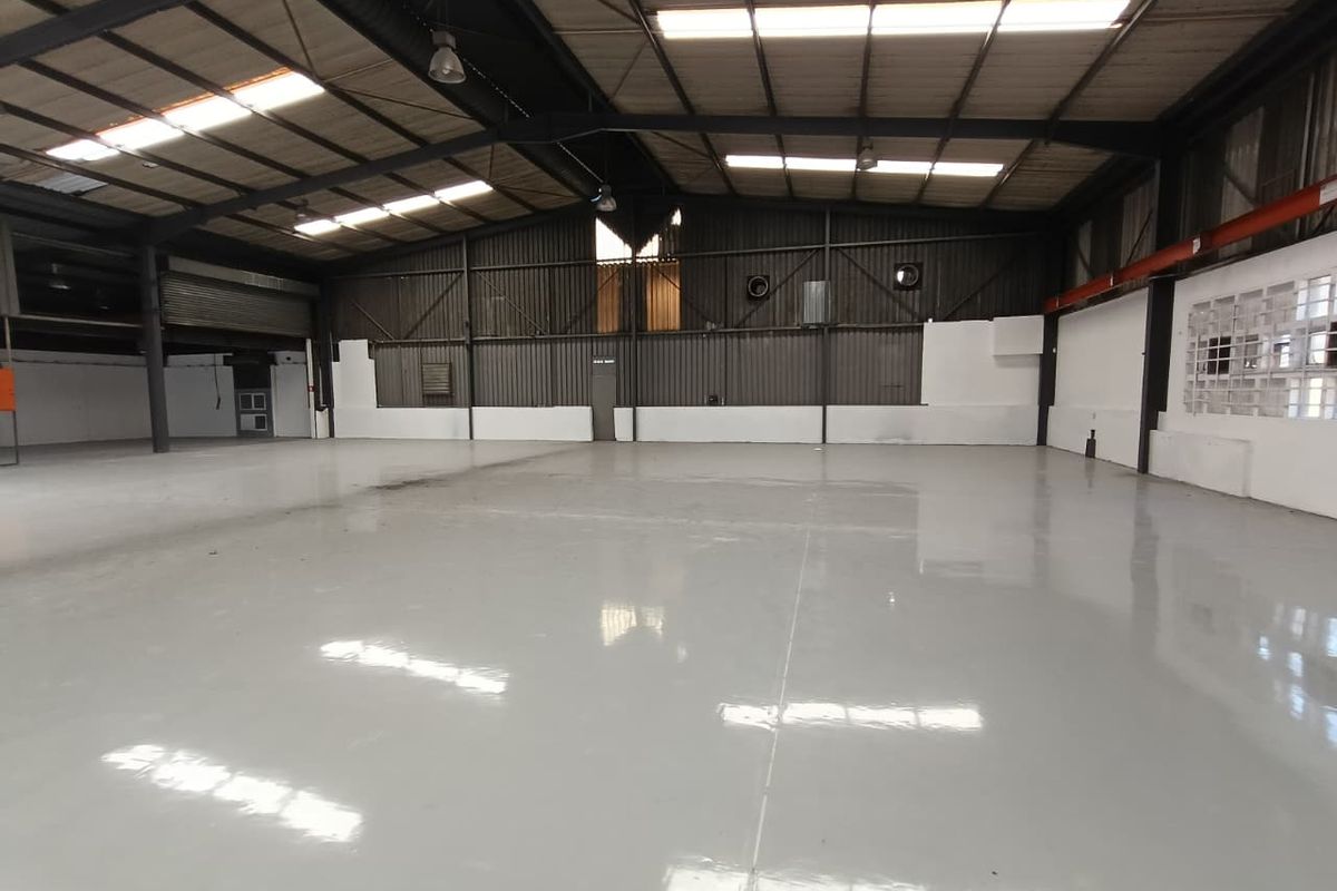 Spacious industrial warehouse featuring a polished epoxy floor, high-clearance steel portal frame, and ample natural light through integrated roof skylights.