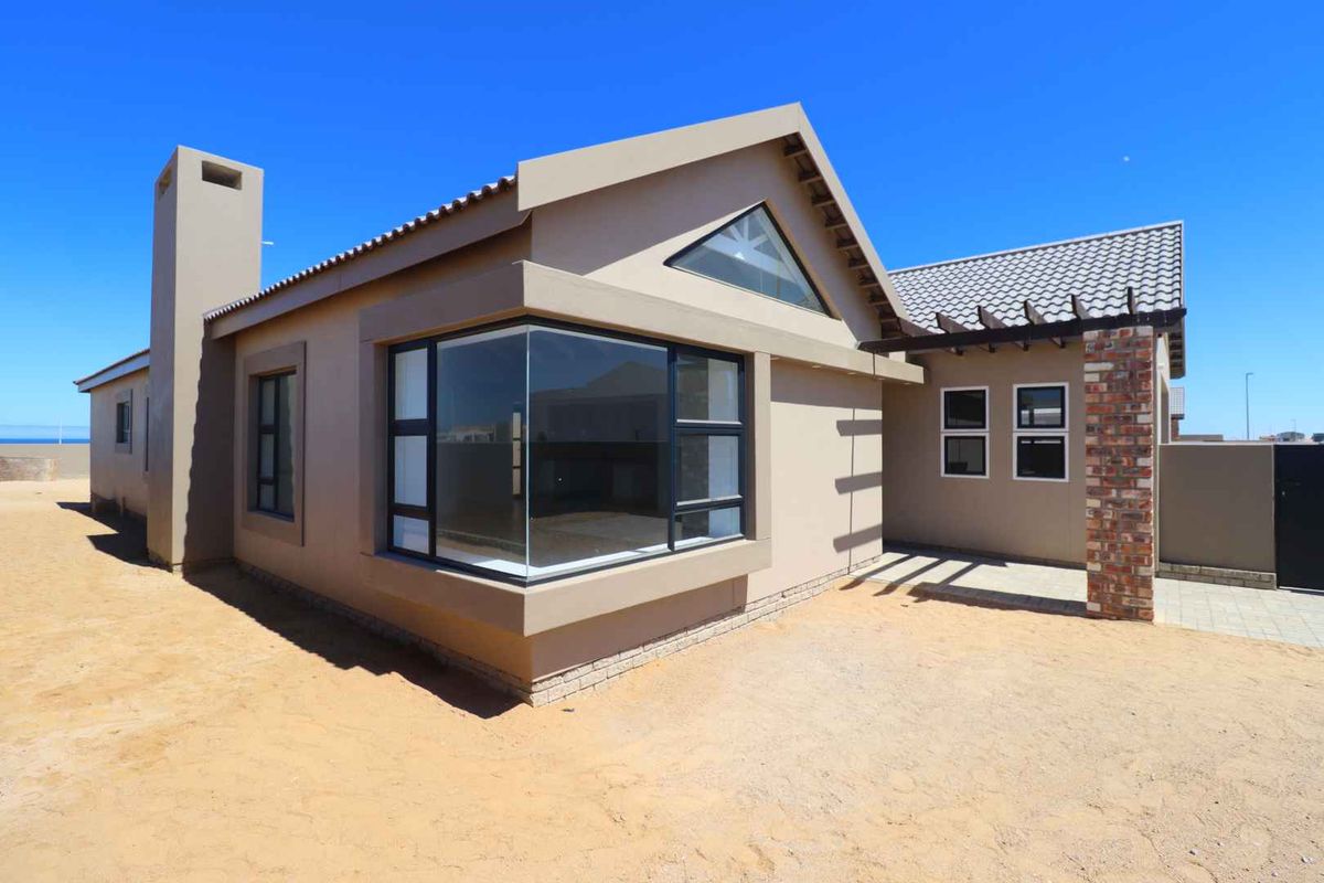Modern exterior view of the house featuring a prominent corner window, pitched roof, and a brick-accented pergola structure.