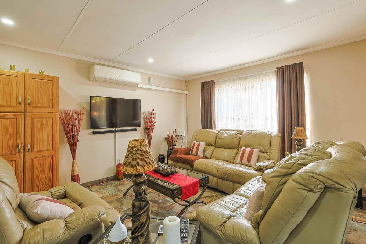 A comfortable living room featuring tiled flooring, recessed downlighting, and a wall-mounted split-system air conditioning unit.