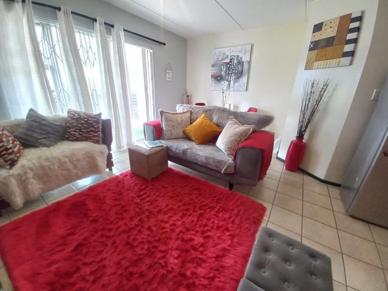 A bright living room featuring tiled flooring and a sliding glass door providing access to the exterior.