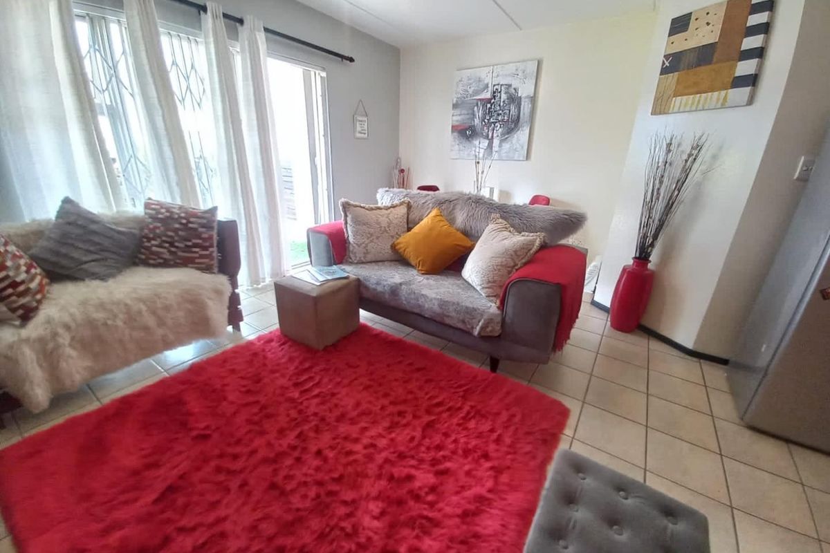 A bright living room featuring tiled flooring and a sliding glass door providing access to the exterior.