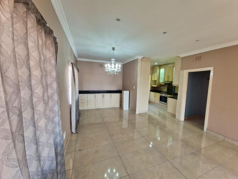 Spacious open-plan living and dining area featuring tiled floors, built-in cabinetry, and a functional kitchen with granite countertops and integrated appliances.