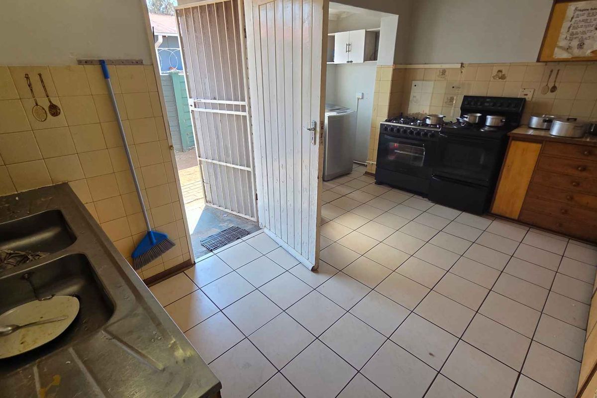 Functional kitchen featuring tiled flooring, built-in cabinetry, a double sink, and a freestanding stove, with direct access to an outdoor area.