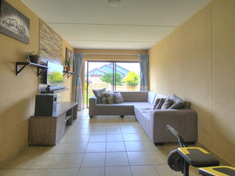 A living room featuring tiled flooring and a large sliding glass door providing access to the rear garden area.