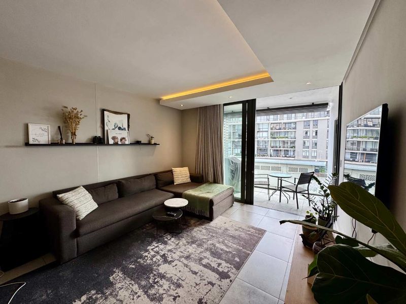 Modern living room featuring recessed ceiling lighting, tiled floors, and a large sliding glass door providing access to a private balcony.