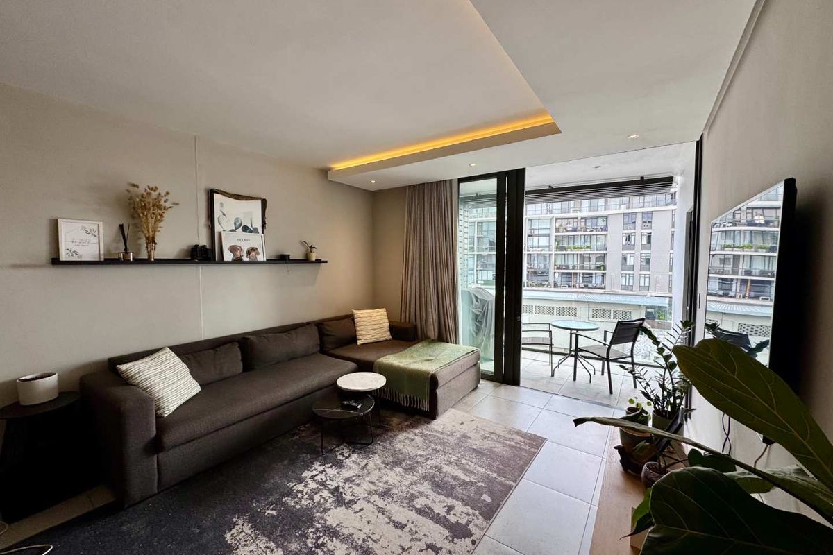 Modern living room featuring recessed ceiling lighting, tiled floors, and a large sliding glass door providing access to a private balcony.