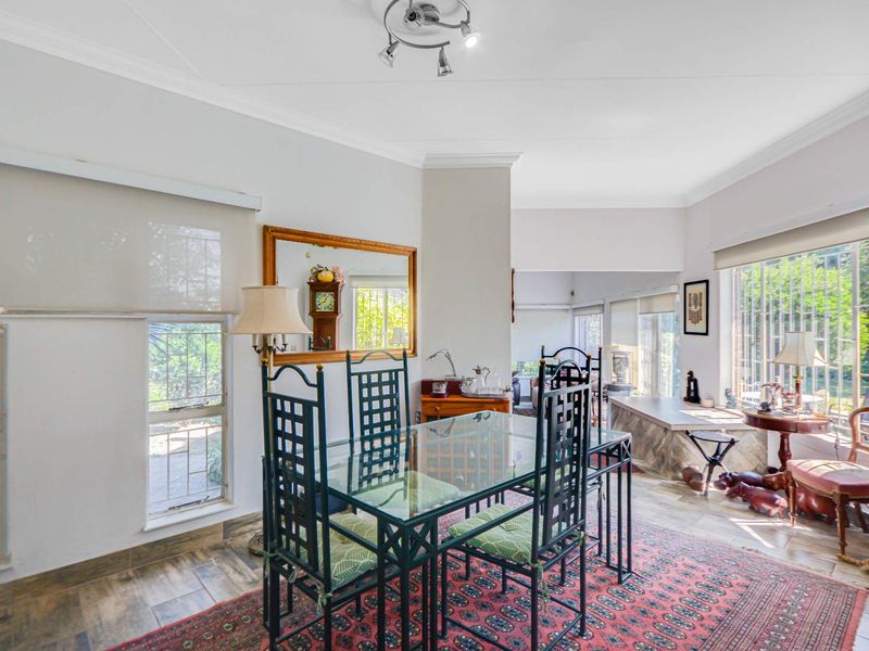 Bright dining area featuring tiled flooring, neutral walls, and large windows with roller blinds, offering a functional space for family meals.