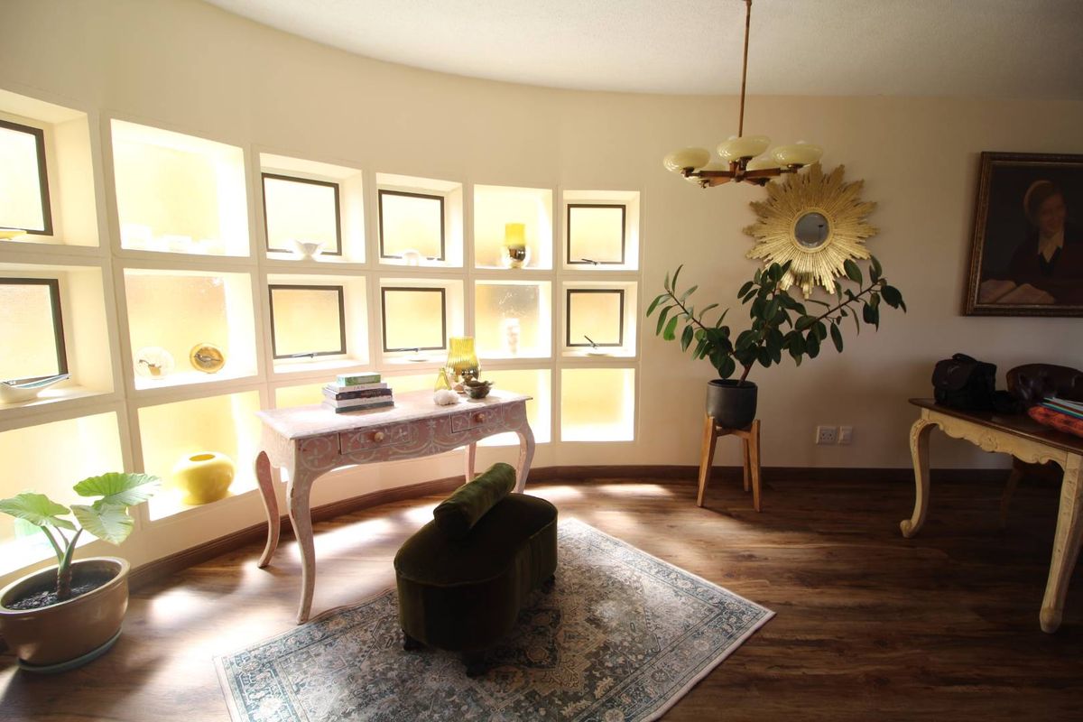 A living area featuring a curved wall with built-in illuminated display shelving and wood-look laminate flooring.