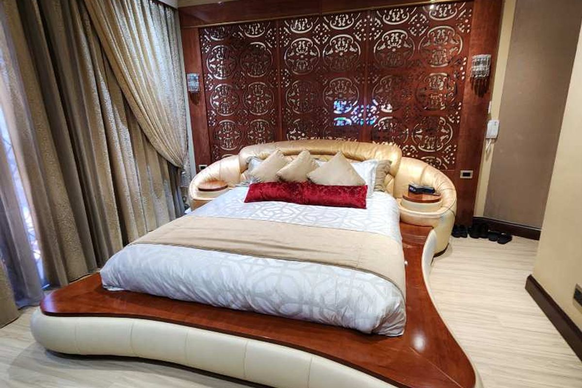 A well-maintained bedroom featuring decorative wood wall paneling, recessed ceiling lighting, and light-toned laminate flooring.
