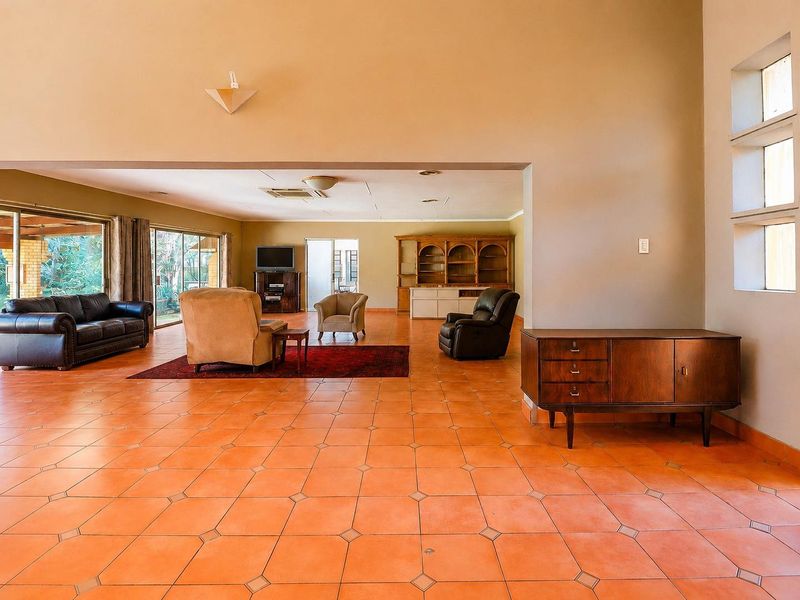 Spacious living area featuring terracotta tile flooring, high ceilings, and large sliding glass doors providing access to the outdoor space.