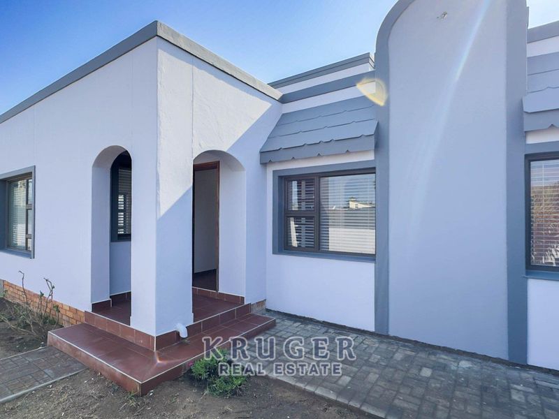 Front elevation of a modern house featuring a tiled entrance porch, arched architectural details, and paved exterior pathways.