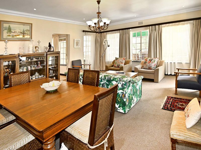 Spacious open-plan living and dining area featuring neutral carpeting, coved ceilings, and large windows that provide ample natural light.