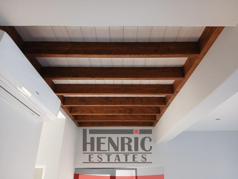 Interior view highlighting exposed timber ceiling beams and a wall-mounted air conditioning unit.