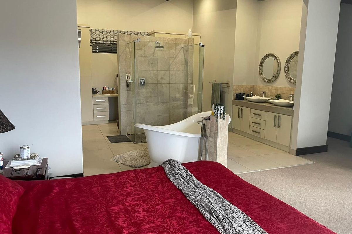 Spacious open-plan bedroom featuring an integrated en-suite bathroom with a freestanding bathtub, glass-enclosed shower, and dual vanity unit.
