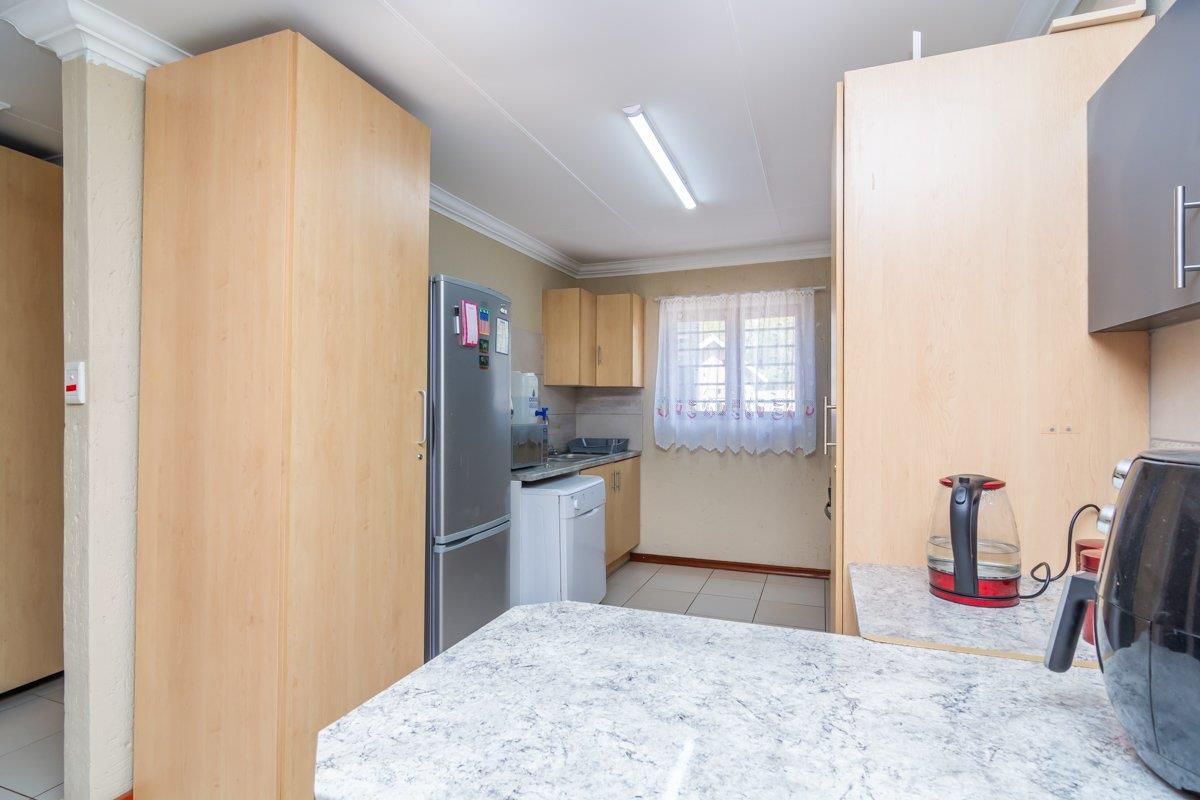 A functional kitchen featuring light wood cabinetry, laminate countertops, and tiled flooring, providing a practical workspace for daily meal preparation.
