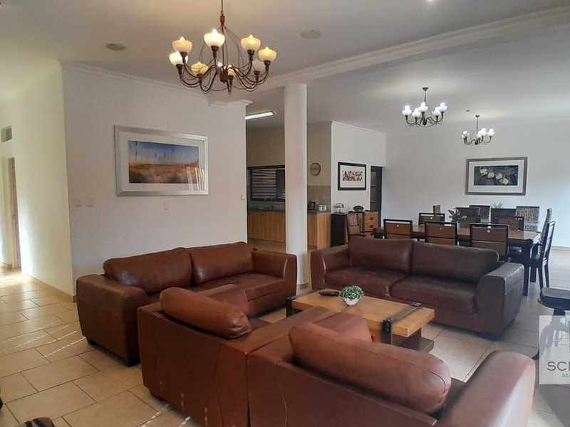 Spacious open-plan living and dining area featuring tiled flooring, recessed lighting, and a central structural column, creating a bright and functional layout.